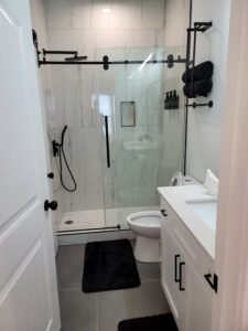 Modern bathroom remodel by Above All Handyman featuring frameless glass shower with matte black fixtures, white vanity with quartz top, and large floor tiles – 1498 Murphy Ave, Atlanta, GA.