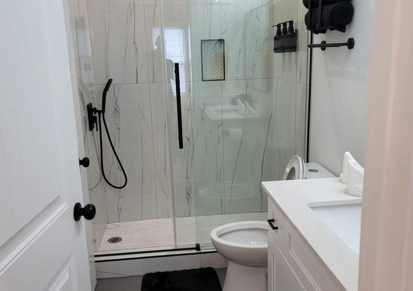 Modern bathroom remodel by Above All Handyman featuring frameless glass shower with matte black fixtures, white vanity with quartz top, and large floor tiles – 1498 Murphy Ave, Atlanta, GA.